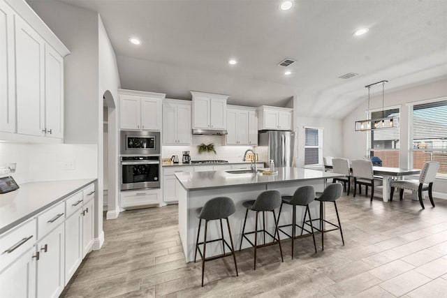 kitchen with pendant lighting, an island with sink, white cabinetry, sink, and stainless steel appliances