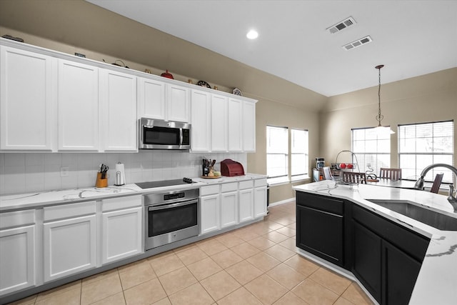 kitchen with sink, appliances with stainless steel finishes, tasteful backsplash, white cabinets, and decorative light fixtures