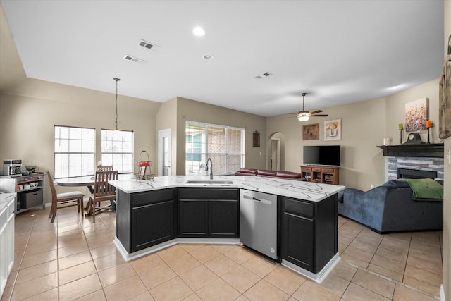 kitchen featuring stainless steel dishwasher, sink, an island with sink, and hanging light fixtures