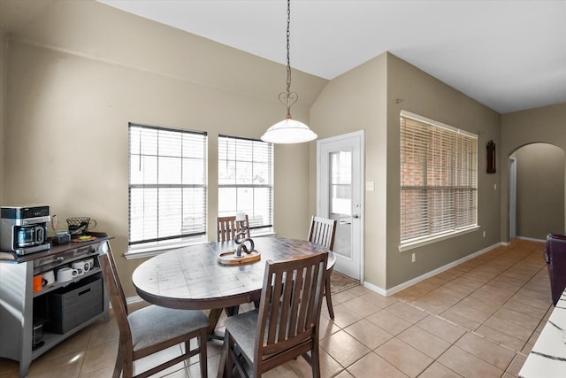 tiled dining room featuring vaulted ceiling