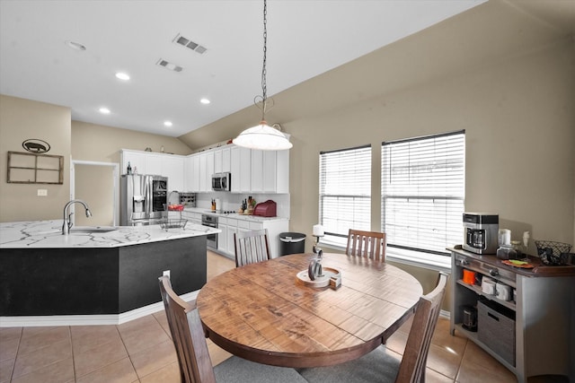 dining room with lofted ceiling, sink, and light tile patterned floors