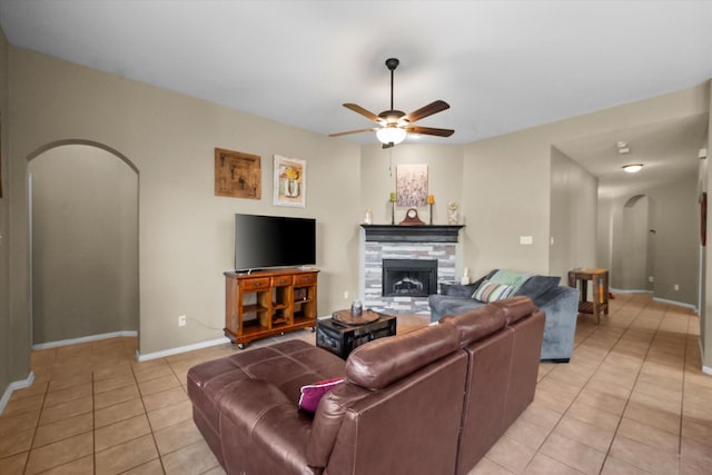 living room with light tile patterned flooring, ceiling fan, and a fireplace