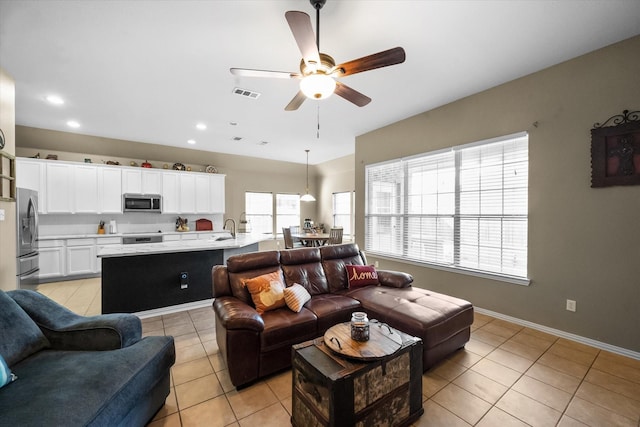 living room featuring ceiling fan, sink, and light tile patterned floors