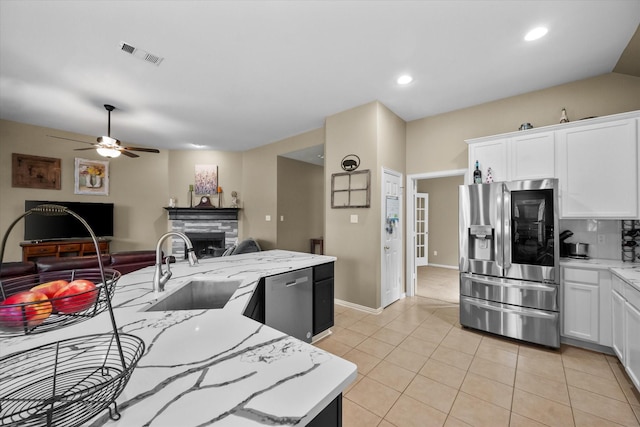 kitchen with sink, light tile patterned floors, white cabinetry, stainless steel appliances, and light stone counters