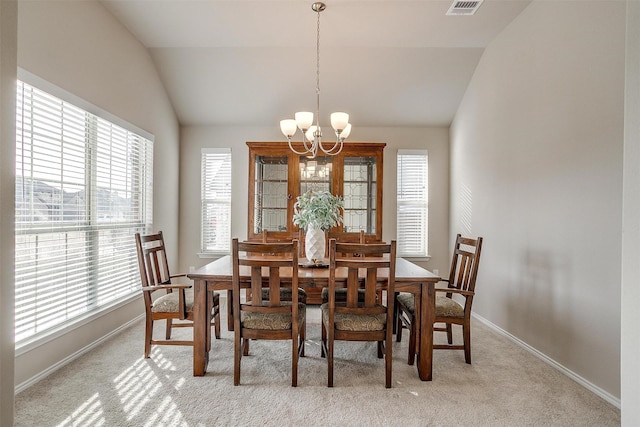 carpeted dining space with vaulted ceiling and an inviting chandelier