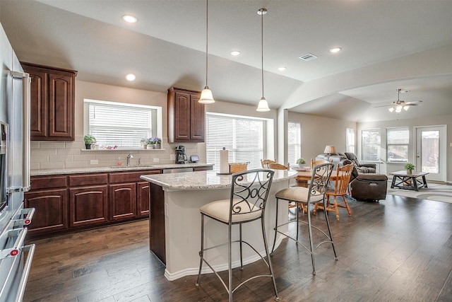 kitchen featuring dark hardwood / wood-style floors, a center island, lofted ceiling, and tasteful backsplash