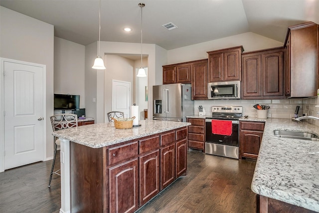 kitchen featuring stainless steel appliances, sink, decorative light fixtures, a center island, and dark hardwood / wood-style floors