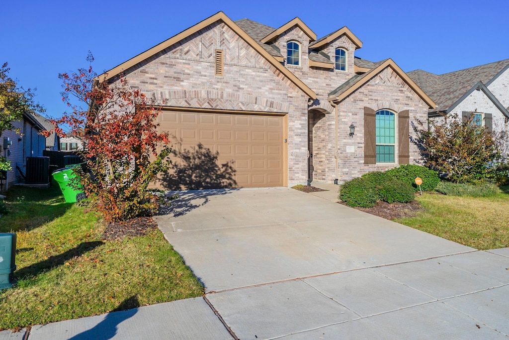 view of front of house featuring central AC unit, a front yard, and a garage