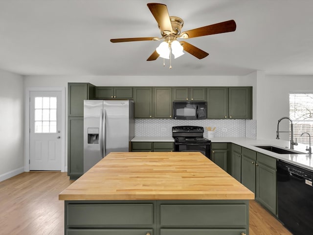 kitchen with backsplash, black appliances, light wood-type flooring, and green cabinetry