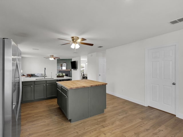 kitchen featuring wooden counters, light wood-type flooring, sink, stainless steel fridge with ice dispenser, and a kitchen island