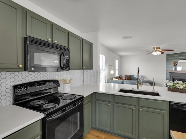 kitchen featuring light wood-type flooring, backsplash, sink, black appliances, and green cabinets