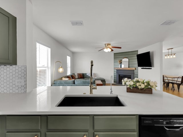 kitchen featuring dishwasher, backsplash, sink, green cabinetry, and ceiling fan