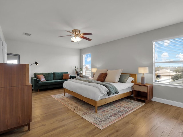 bedroom with multiple windows, light wood-type flooring, and ceiling fan