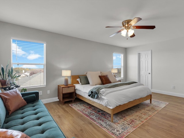 bedroom with multiple windows, ceiling fan, and light wood-type flooring