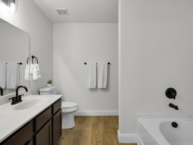 bathroom featuring a bath, vanity, wood-type flooring, and toilet