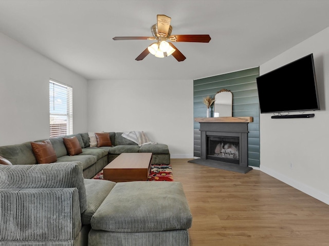 living room with a fireplace, light hardwood / wood-style floors, and ceiling fan