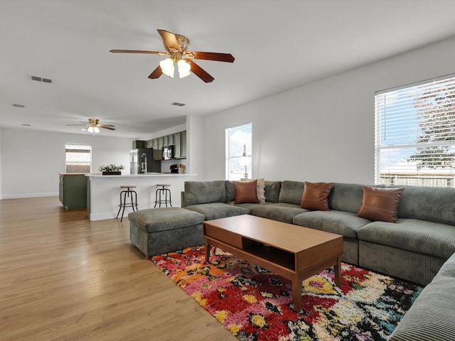 living room featuring light hardwood / wood-style flooring, plenty of natural light, and ceiling fan