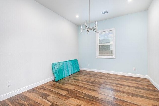 spare room featuring dark hardwood / wood-style floors and a chandelier