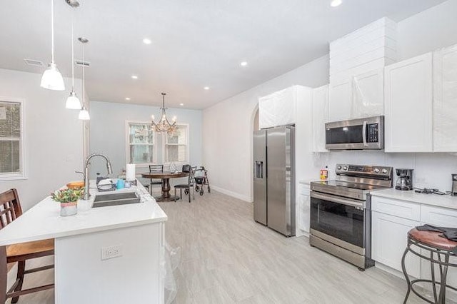 kitchen with sink, a kitchen breakfast bar, a center island with sink, white cabinets, and appliances with stainless steel finishes