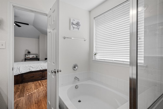 bathroom featuring lofted ceiling, wood-type flooring, and a bath