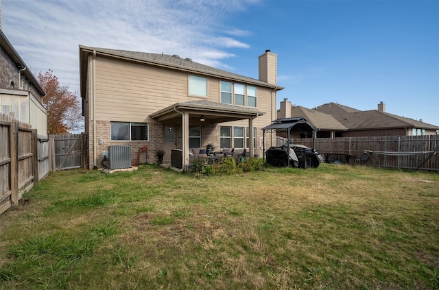 rear view of house with cooling unit, a yard, and a patio area