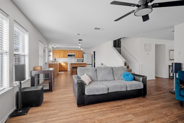 living room featuring ceiling fan, sink, light hardwood / wood-style flooring, and a healthy amount of sunlight