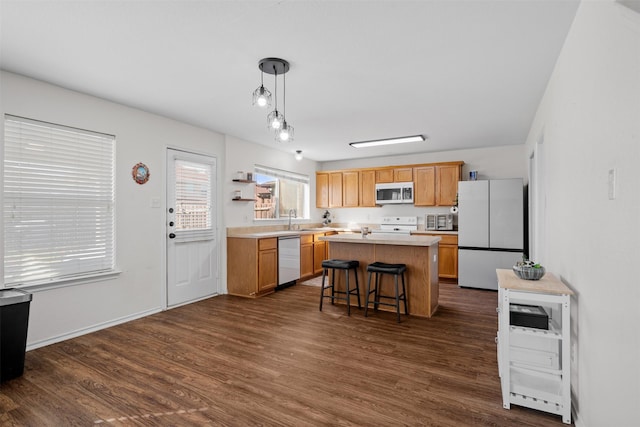 kitchen with appliances with stainless steel finishes, a center island, a kitchen bar, dark hardwood / wood-style flooring, and decorative light fixtures