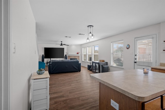 kitchen featuring pendant lighting, ceiling fan, dark wood-type flooring, and a kitchen island