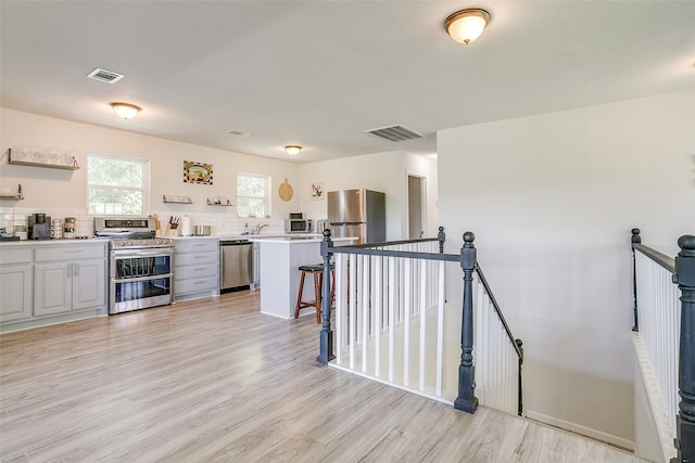 kitchen featuring a breakfast bar, sink, appliances with stainless steel finishes, and light hardwood / wood-style flooring