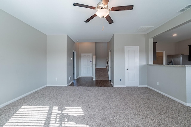 unfurnished room with ceiling fan and dark carpet