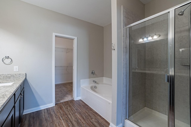 bathroom featuring hardwood / wood-style flooring, vanity, and plus walk in shower