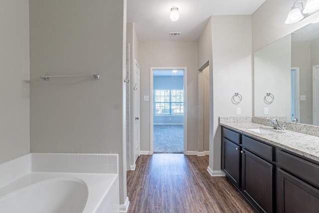 bathroom featuring a bathing tub, vanity, and wood-type flooring