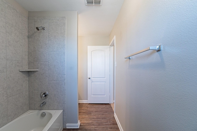 bathroom featuring hardwood / wood-style flooring and tiled shower / bath