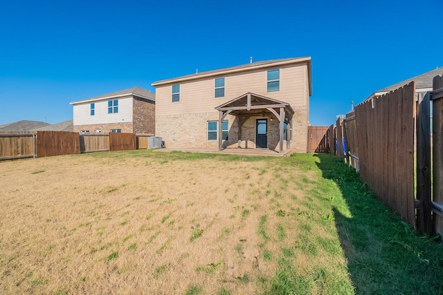 back of property with a lawn, a patio area, and central air condition unit