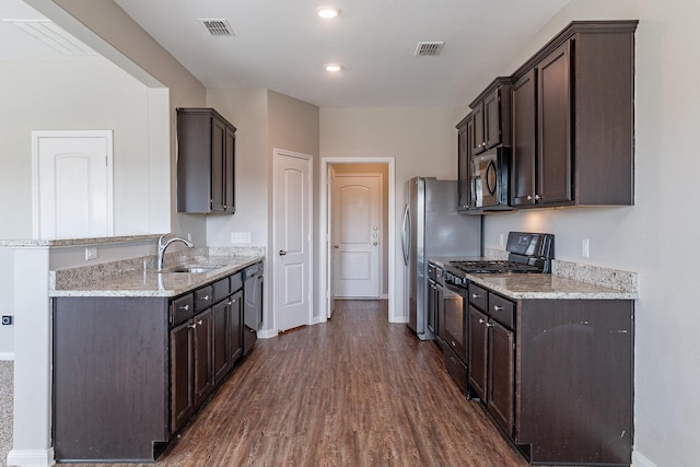 kitchen with appliances with stainless steel finishes, dark hardwood / wood-style floors, dark brown cabinets, and sink