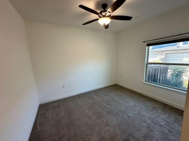 spare room featuring ceiling fan and dark carpet