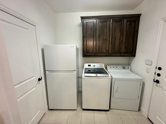 clothes washing area featuring washer and dryer and cabinets