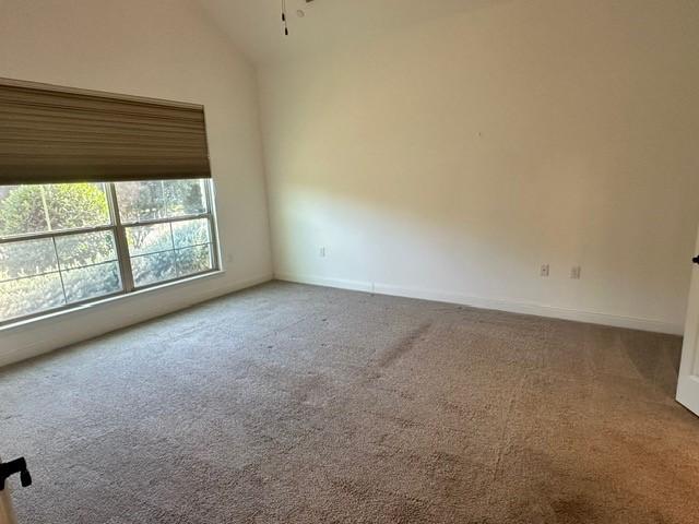 carpeted empty room featuring lofted ceiling