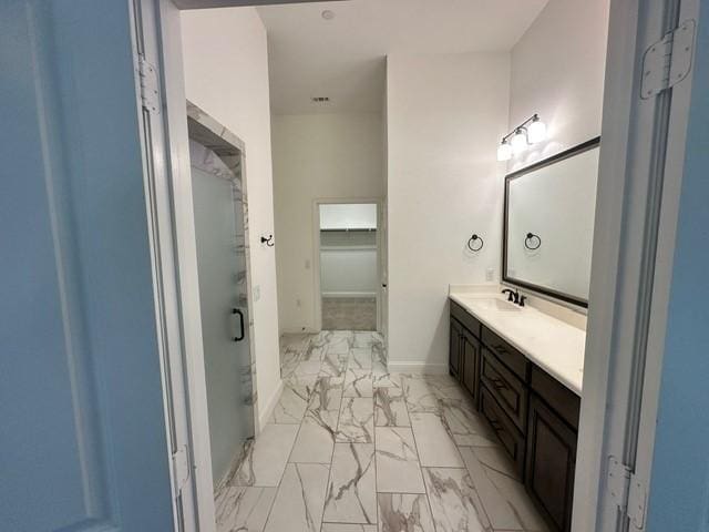 bathroom featuring a shower with shower door and vanity