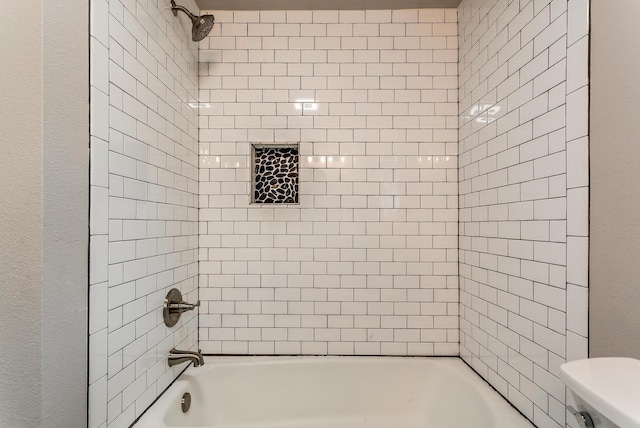 bathroom featuring toilet and tiled shower / bath