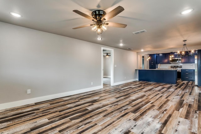 unfurnished living room with ceiling fan with notable chandelier and dark hardwood / wood-style floors