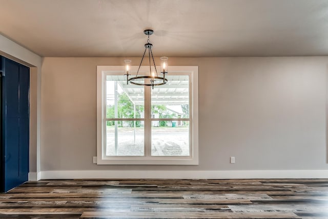 unfurnished dining area with a chandelier and dark wood-type flooring