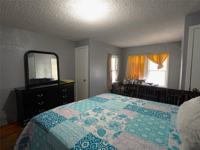 bedroom with a textured ceiling and dark hardwood / wood-style floors