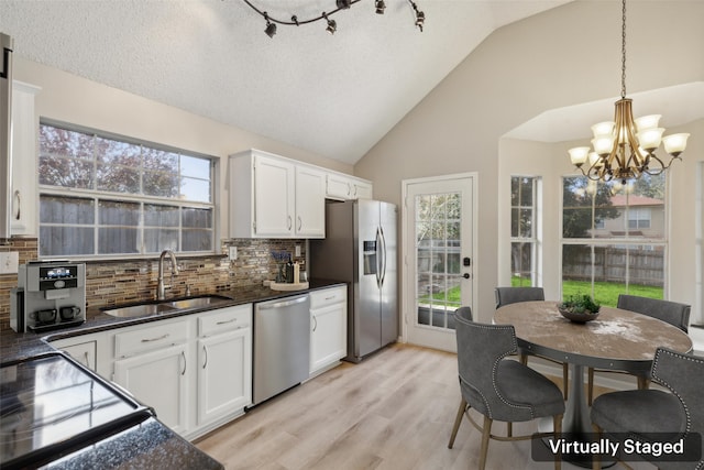 kitchen featuring stainless steel appliances, sink, white cabinets, and pendant lighting