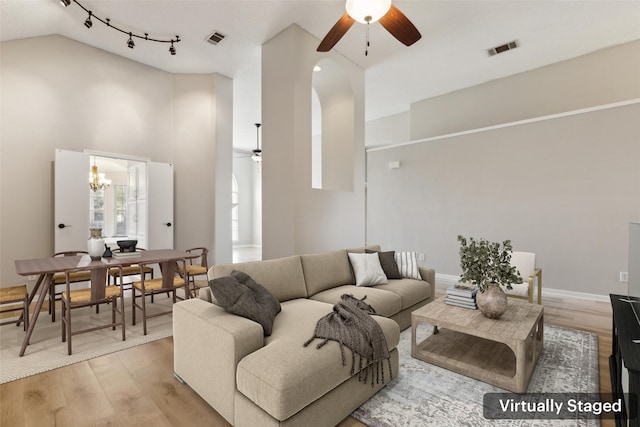 living room with ceiling fan with notable chandelier, light hardwood / wood-style floors, and lofted ceiling