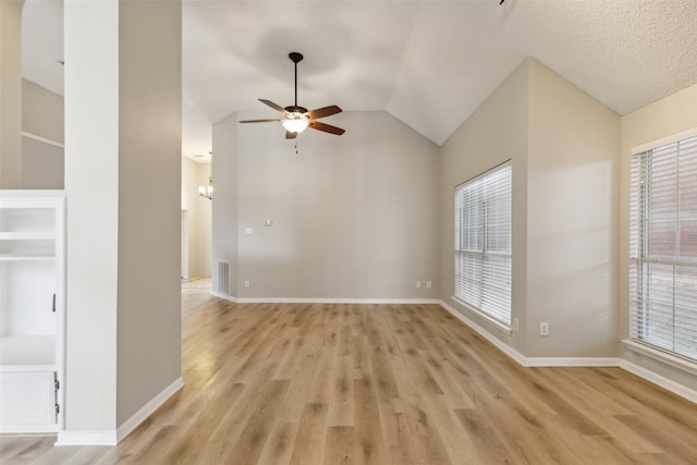 unfurnished room with a wealth of natural light, light hardwood / wood-style flooring, ceiling fan with notable chandelier, and lofted ceiling