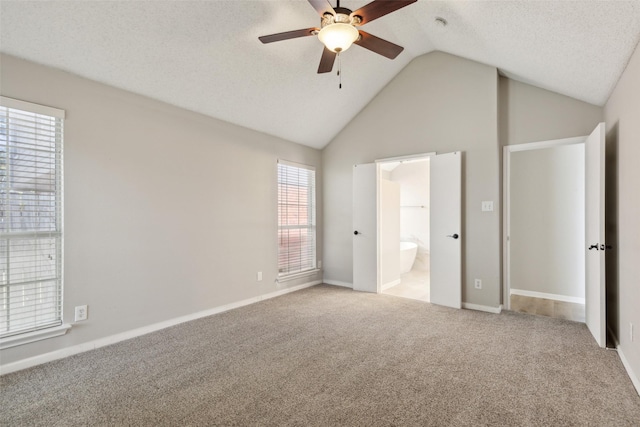 unfurnished bedroom with ensuite bath, ceiling fan, carpet floors, a textured ceiling, and vaulted ceiling