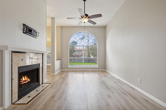 unfurnished living room with a fireplace, a textured ceiling, light hardwood / wood-style flooring, and ceiling fan