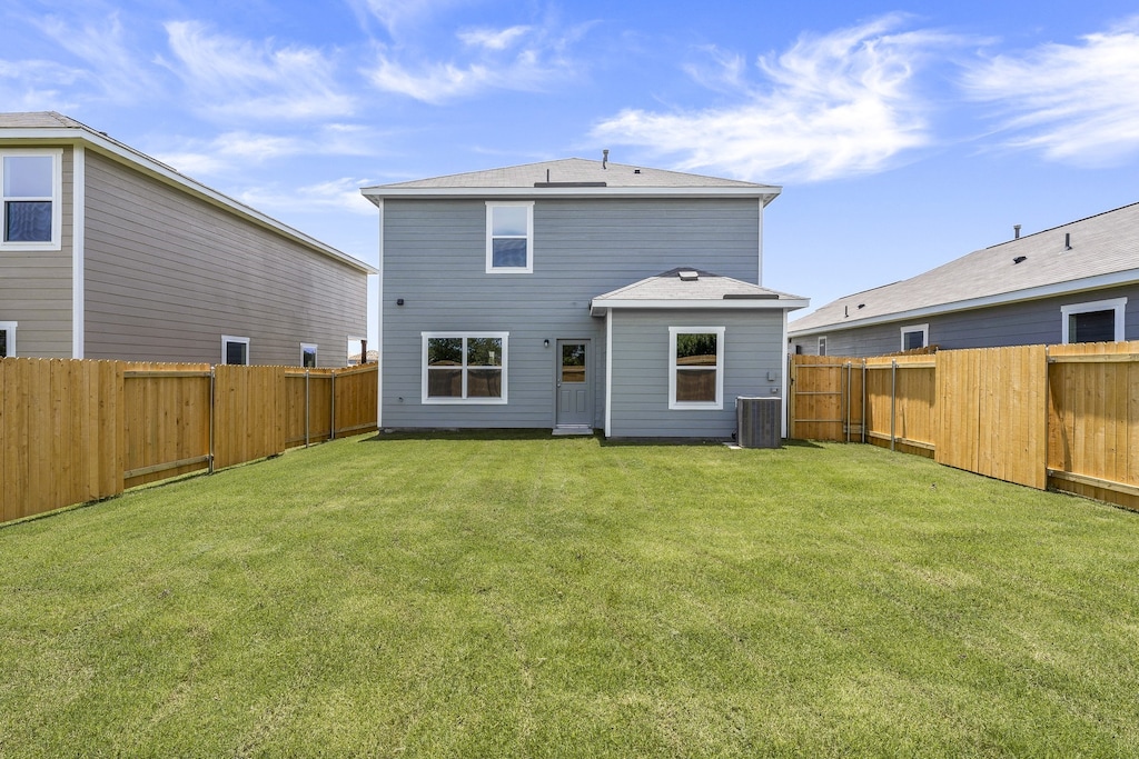 rear view of house featuring a yard and central air condition unit