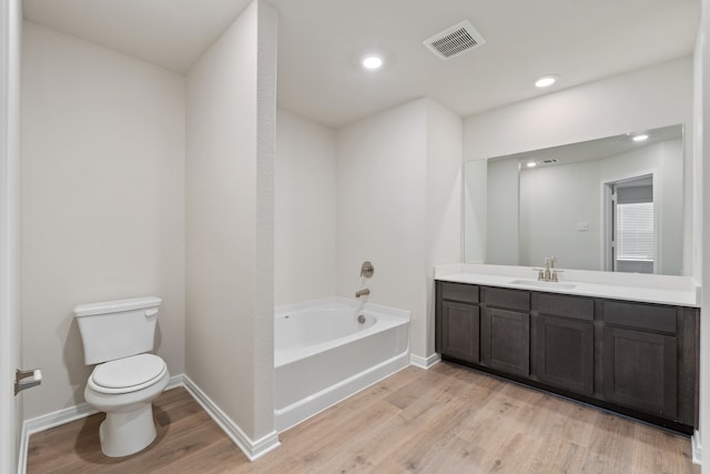 bathroom with a washtub, hardwood / wood-style floors, vanity, and toilet